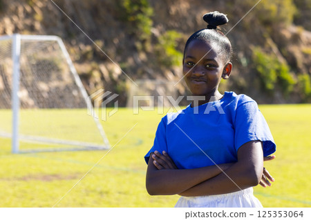 On soccer field, african american girl in blue shirt crossing arms, smiling, copy space On soccer field, african american girl in blue shirt crossing arms, smiling, copy space 125353064