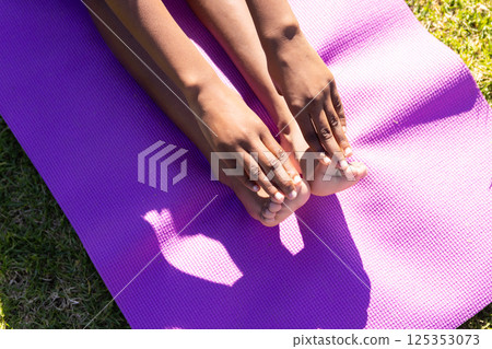 Stretching on yoga mat, african american girl touching toes during outdoor exercise at school 125353073