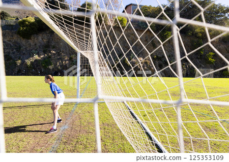 Playing soccer, girl in goalkeeping position on school field, ready to defend Playing soccer, girl in goalkeeping position on school field, ready to defend 125353109