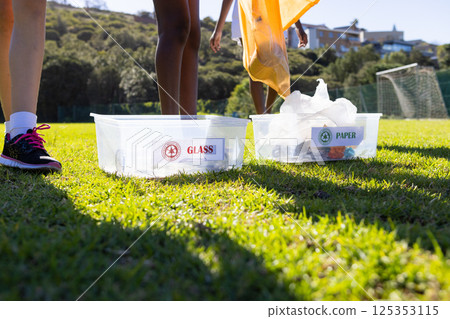 Recycling at school, diverse girls sorting glass and paper into separate bins 125353115