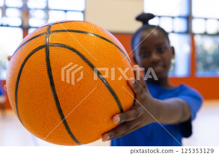 Holding basketball, african american girl in school gym smiling and looking at camera 125353129