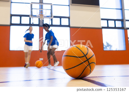 Playing basketball in school gym, diverse girls dribbling and practicing skills 125353167