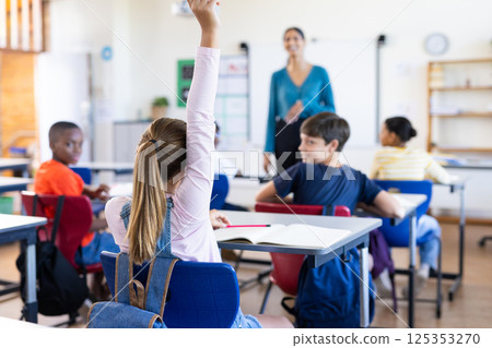 In school, student raising hand to answer question in classroom with Indian female teacher 125353270