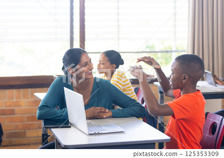 In school, Indian female teacher with laptop engaging with students in classroom discussion In school, Indian female teacher with laptop engaging with students in classroom discussion 125353309