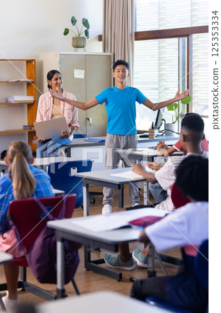 Presenting in classroom, boy engaging indian female teacher and students watching in school Presenting in classroom, boy engaging indian female teacher and students watching in school 125353334