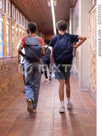 Walking in school hallway, students with backpacks heading to class Walking in school hallway, students with backpacks heading to class 125353352