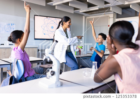 Engaging students in science classroom, Indian female teacher using microscope and beakers 125353378