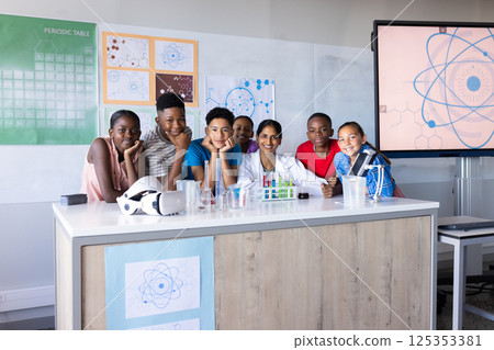 Smiling in science classroom, Indian female teacher and group of students with lab equipment 125353381