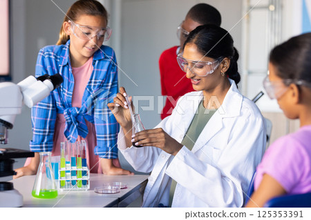 In school, Indian female teacher demonstrating science experiment to students with test tubes In school, Indian female teacher demonstrating science experiment to students with test tubes 125353391