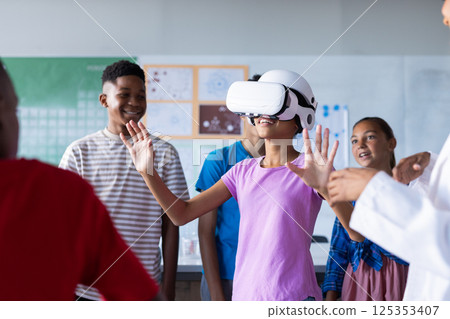 Using VR headset, students in school classroom exploring virtual reality together Using VR headset, students in school classroom exploring virtual reality together 125353407