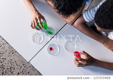 Conducting science experiment with colorful liquids and petri dishes, students in school 125353409