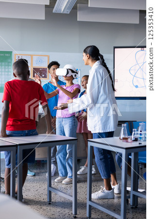 In school, students using VR headset in classroom with Indian female teacher guiding them In school, students using VR headset in classroom with Indian female teacher guiding them 125353410