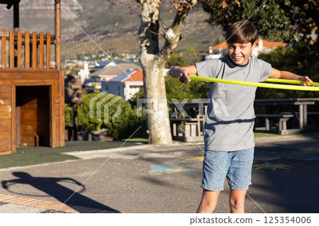 Playing with hula hoop, boy enjoying outdoor activity at school playground, copy space Playing with hula hoop, boy enjoying outdoor activity at school playground, copy space 125354006