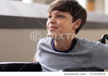 Smiling boy in wheelchair looking up, enjoying moment at school 125354050