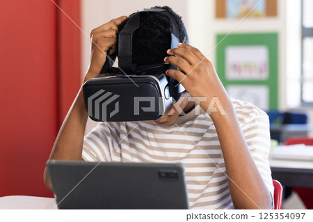 Using VR headset, student exploring virtual reality with tablet in school classroom 125354097