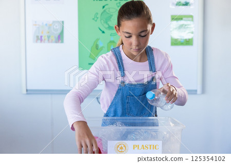 Recycling plastic bottles, girl in school classroom focusing on sustainability Recycling plastic bottles, girl in school classroom focusing on sustainability 125354102
