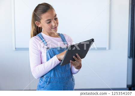 Using tablet, girl in school classroom focusing on digital learning 125354107