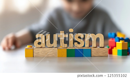Child with autism playing: wooden block AUTISM letters and colorful toys 125355102