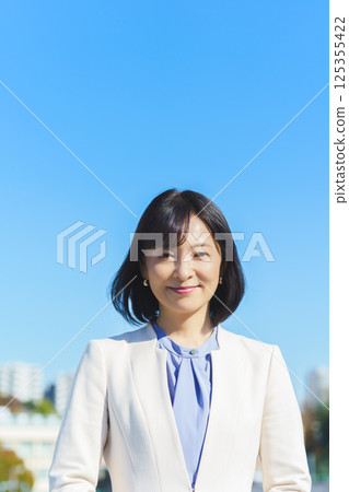 A middle-aged career woman in a white suit under a blue sky A middle-aged career woman in a white suit under a blue sky 125355422
