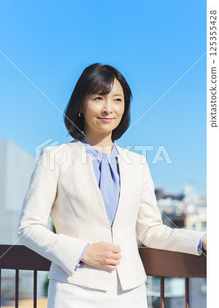 藍天下身穿白色西裝的中年職業女性 125355428