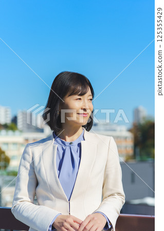 藍天下身穿白色西裝的中年職業女性 125355429