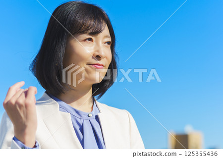 藍天下身穿白色西裝的中年職業女性 藍天下身穿白色西裝的中年職業女性 125355436