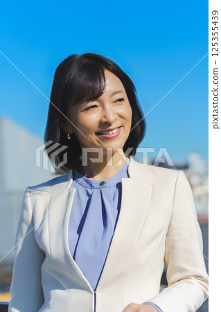 藍天下身穿白色西裝的中年職業女性 藍天下身穿白色西裝的中年職業女性 125355439