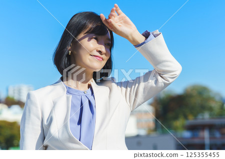 A middle-aged career woman in a white suit under a blue sky A middle-aged career woman in a white suit under a blue sky 125355455