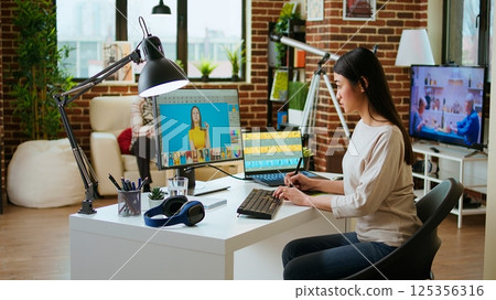 Expert artist woman edits digital photos on her computer in a creative office. Her home workspace equipped with editing software, enhancing artistic work in the industry. Camera A. Expert artist woman edits digital photos on her computer in a creative office. Her home workspace equipped with editing software, enhancing artistic work in the industry. Camera A. 125356316