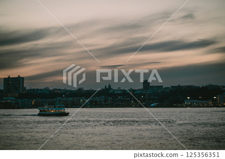 A boat floats on water with a city in the background 125356351