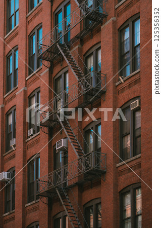 There is a brick building that features a fire escape on its side There is a brick building that features a fire escape on its side 125356352