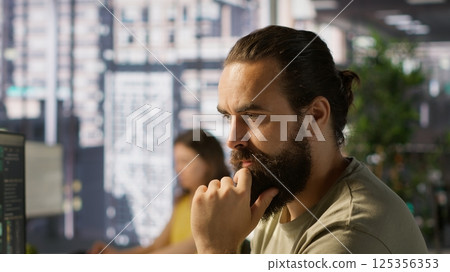 Pensive employee using computer to analyze datasets, focused on comparing datasets and checking accounting figures. Close up of man concentrating on solving tasks for team project, camera A 125356353