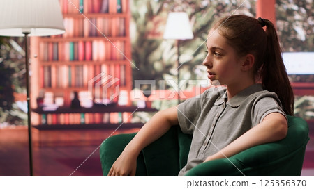 Teen girl in a confidential therapy session discussing personal challenges like anxiety, social issues and depression. Psychologist supports her emotional well being and mental resilience. Camera A. 125356370