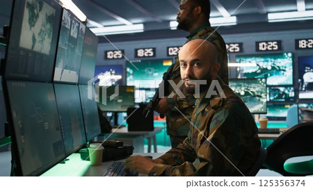 Military officers checking weapons in control room, ensuring bullets and supplies are properly and evenly distributed. Soldiers managing combat load equipment before warfare assault mission, camera B Military officers checking weapons in control room, ensuring bullets and supplies are properly and evenly distributed. Soldiers managing combat load equipment before warfare assault mission, camera B 125356374