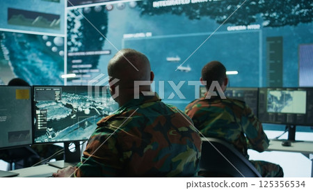 Soldier in a secure environment ensuring data analysis and processing, gathering intelligence for strategic planning to ensure a successful defense mission. Secret service activity. Camera B. 125356534