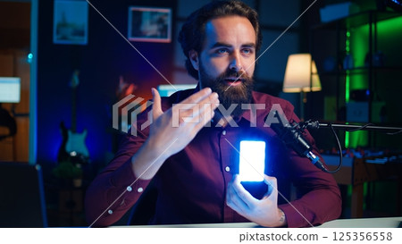 Tech guru filming technology review of mini led lights, offering feedback, close up shot. Friendly online star showing filming equipment to subscribers, talking in mic, camera B 125356558