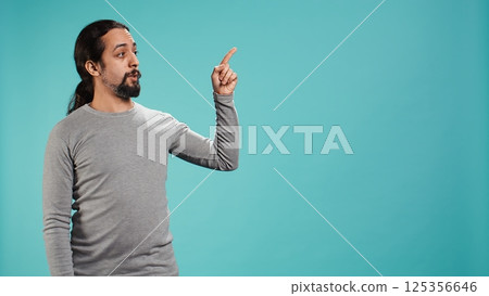 Salesman pointing around with finger, doing recommendation, talking with audience. Man showing copy text space, doing advertisement, isolated over studio background, camera B Salesman pointing around with finger, doing recommendation, talking with audience. Man showing copy text space, doing advertisement, isolated over studio background, camera B 125356646