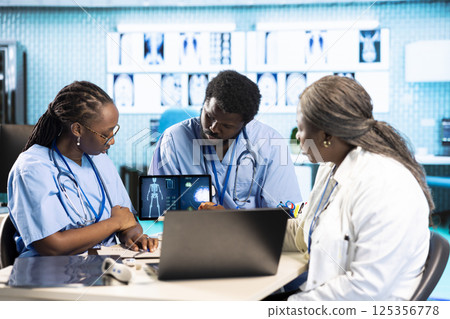 Team of male and female african american medical staff discussing diagnostic results with a medic expert in a modern cabinet. Advanced technology and healthcare services at clinic. Team of male and female african american medical staff discussing diagnostic results with a medic expert in a modern cabinet. Advanced technology and healthcare services at clinic. 125356778