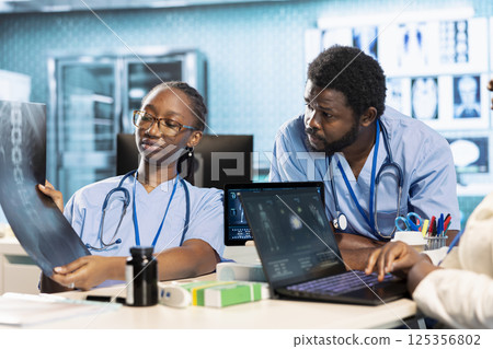 Team of trainee nurses analyzing patient health records during a meeting, utilizing x ray and mri scans with expert physician for a training session. Assistants work with medic. Team of trainee nurses analyzing patient health records during a meeting, utilizing x ray and mri scans with expert physician for a training session. Assistants work with medic. 125356802