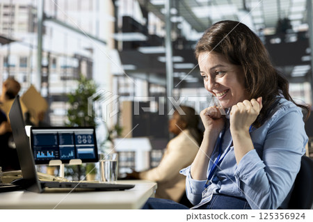 Happy business worker celebrating a major project milestone at her desk, thrilled with the successful outcome. Enthusiastic woman smiles and enjoys good news, satisfied of professional victory. Happy business worker celebrating a major project milestone at her desk, thrilled with the successful outcome. Enthusiastic woman smiles and enjoys good news, satisfied of professional victory. 125356924