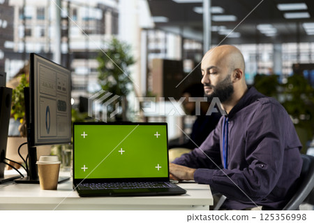 Young corporate analyst handling financial tasks next to chroma key display, preparing a project briefing for the multinational company. Manager reviewing numbers and performance metrics. Young corporate analyst handling financial tasks next to chroma key display, preparing a project briefing for the multinational company. Manager reviewing numbers and performance metrics. 125356998