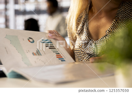 Corporate businesswoman reviewing data analytics at work, doing report writing to ensure project progress. Multinational company worker managing deadlines and financial planning. Close up. Corporate businesswoman reviewing data analytics at work, doing report writing to ensure project progress. Multinational company worker managing deadlines and financial planning. Close up. 125357030