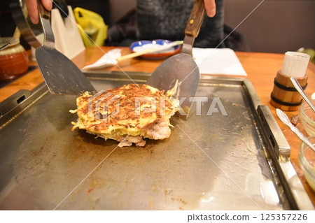 A man flipping an okonomiyaki 125357226