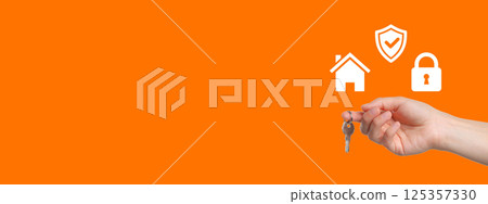 Keys are being held in a hand with symbols of home security on a bright background Keys are being held in a hand with symbols of home security on a bright background 125357330