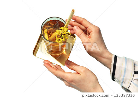 A person holds a glass of iced tea with a fresh garnish on a tray, isolated on white A person holds a glass of iced tea with a fresh garnish on a tray, isolated on white 125357336