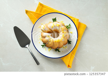 Lemon cake on plate and towel on gray background, top view 125357347