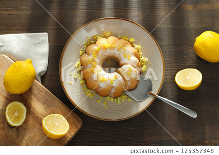 Lemon cake on plate, wooden board and lemon on wooden background, top view Lemon cake on plate, wooden board and lemon on wooden background, top view 125357348