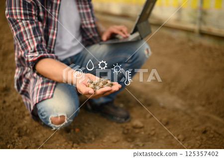 Hand inspecting soil with futuristic icons showing nutrient composition, pH and temperature levels 125357402
