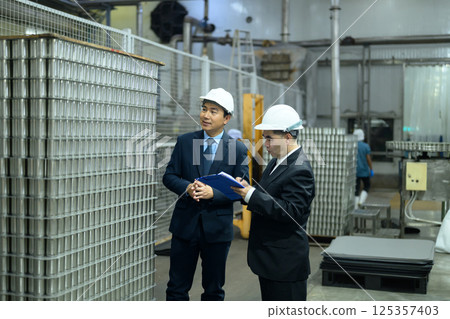 Two business professionals reviewing operations in a food production facility 125357403