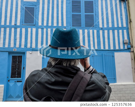 Back of a male tourist photographer with blue hat photographing historical blue landmarks in 125357636